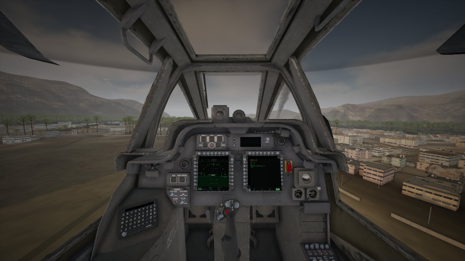 The view from the Apache pilot's rear seat: the front canopy frames, the instrument panel with its two live displays and the town below.